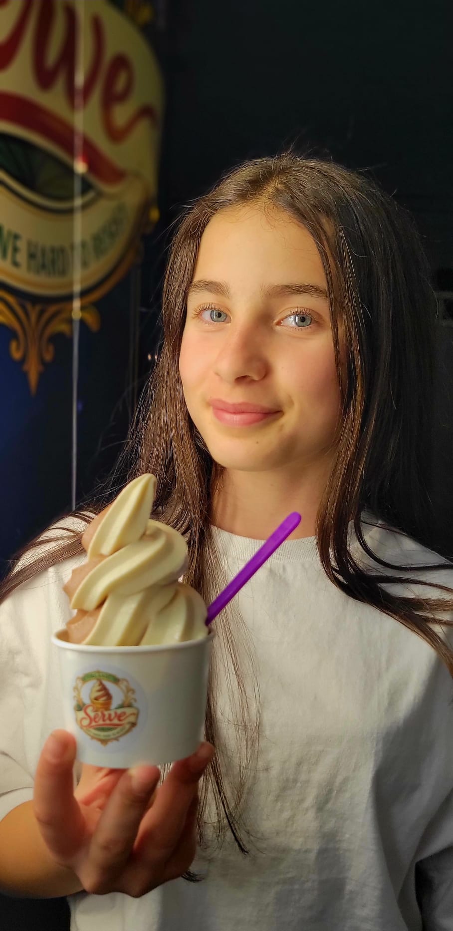 A young guest holding a chocolate-vanilla swirl in a Serve-branded cup.